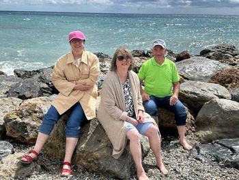 Drei Menschen mit Behinderung sitzen am Strand von Pietra Ligure.