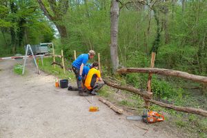 Zwei Mitarbeiter der Grünen Hand reparieren einen Zaun am Biotoprand.